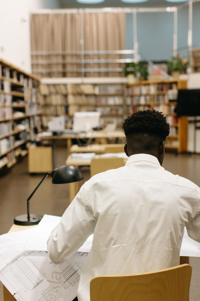 Architect reviewing plans in a modern library setting, emphasizing focus and creativity.